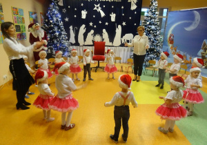 Pani dyrektor Maria Królikowska i pani Ewelina Cicha tańczą z dziećmi w kole.